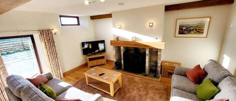 Ein Wohnzimmer mit Sofas, Kamin, Fernseher und Fenster.