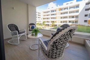 Een balkon met rieten stoelen, een klein rond tafeltje en een plant in pot.