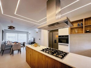 Een moderne keuken met een centraal eiland, een inbouwoven en roestvrijstalen apparatuur.