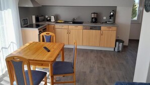 A modern kitchen with wooden cabinets, a dining table with chairs, and a window providing natural light. - NEW! "Nordseeluft" Vacation Rental (Dornum)