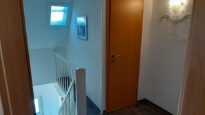 A wooden door, a white railing, a small window, and a wall-mounted light fixture. - NEW! "Nordseeluft" Vacation Rental (Dornum)