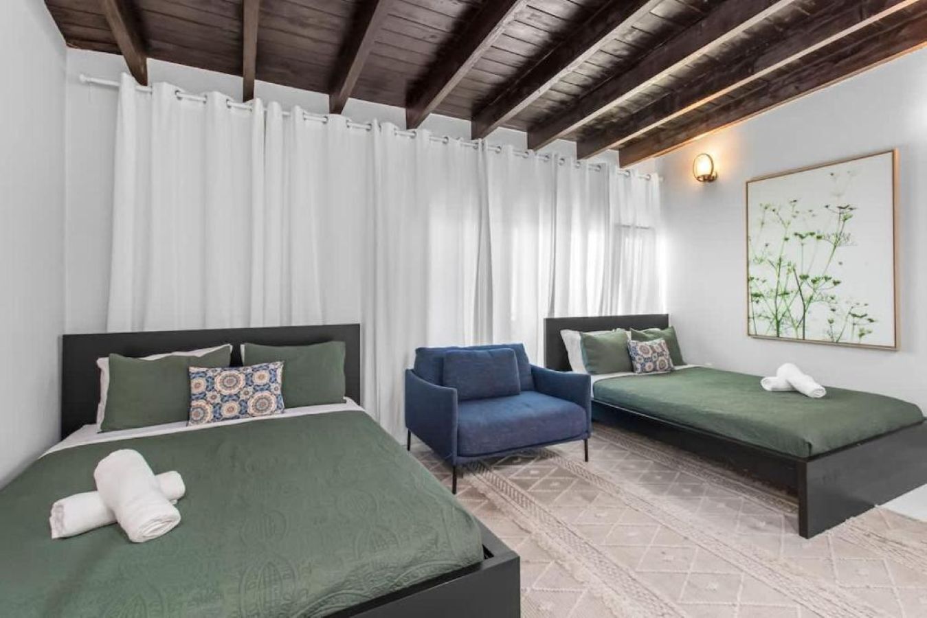 Ein Hotelzimmer mit zwei Betten, einem Sessel und einem Bild an der Wand.