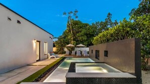 A modern pool area with a clear view of the pool, lounge chairs, and a white building. - Luxury Miami Stay by Glam Homes (North Miami Beach)