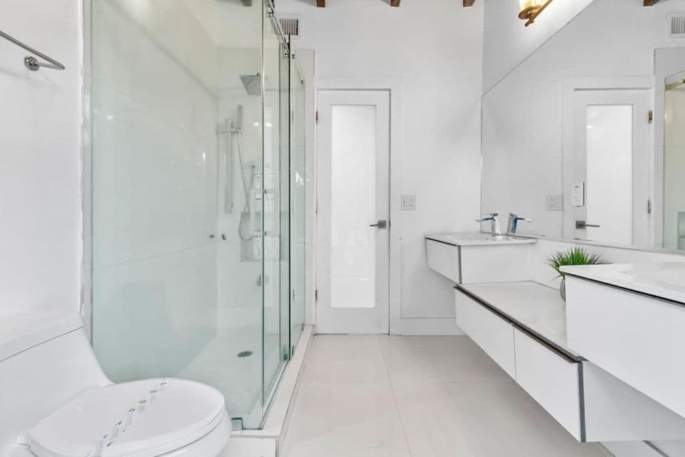 A modern bathroom with a glass shower enclosure, a white toilet, and a vanity with a mirror.