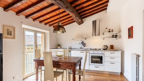 Una cocina con vigas de madera, armarios blancos, una mesa de comedor y sillas.