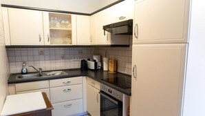 A compact kitchen with a sink, stove, and cabinets.
