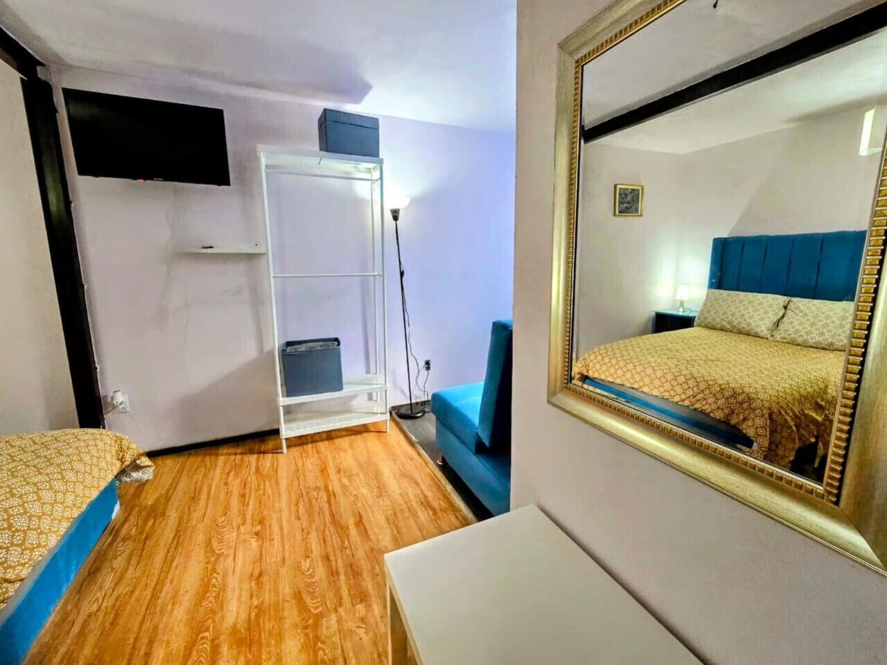 A hotel room with a bed, a desk, a chair, a wardrobe, and a mirror.