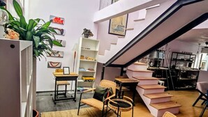 A modern interior with a staircase, wicker furniture, and a bookshelf.
