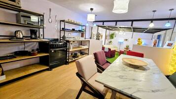 A compact kitchen with modern appliances, a dining area with a marble table, and a cozy seating arrangement.