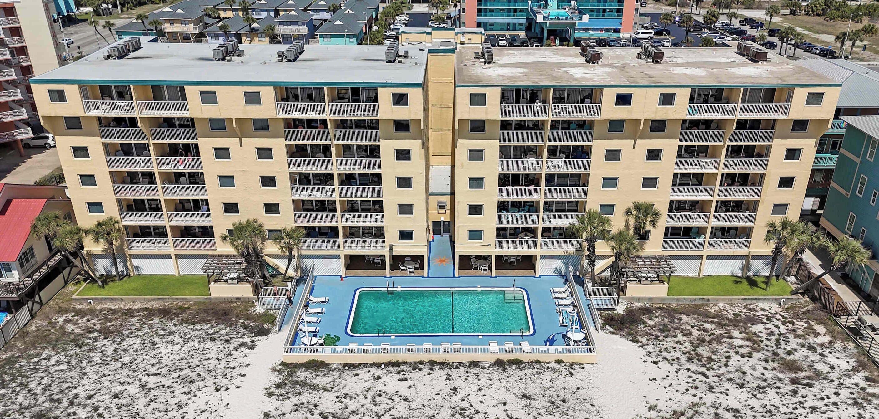 A multi-story hotel with a rooftop pool, balconies, and a beachside location.