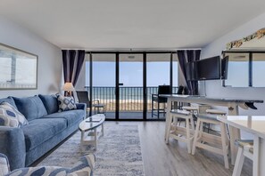 Una habitació amb sofà, taula de cafè, televisió i un balcó amb vistes.