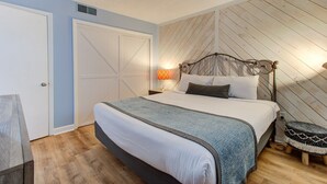 A bedroom with a bed, a nightstand, a lamp, and a wall-mounted heater. - Experience oceanfront bliss at 0309 The Blue Depth in Carolina Beach (Carolina Beach)