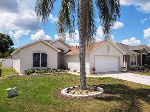 A single-story house with a garage, a well-maintained lawn, and a palm tree in the front yard. - E511JA - Our Happy Place 3B/2bath - Pool & Arcade (Davenport)