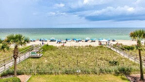 A beach with umbrellas, a wooden walkway, and a sign indicating a private area. - Charming 2BR oceanfront condo with stunning views at Carolina Beach 0314 (Carolina Beach)