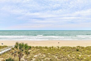 Ein Strand mit einer Holzpromenade, Sandstrand und Wellen.