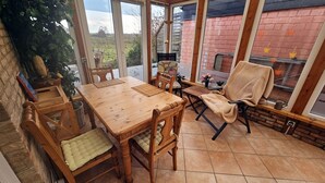 A conservatory with a wooden dining table, chairs, and a bench. - Baltic Sea, Schlei and surroundings (Norderbrarup)