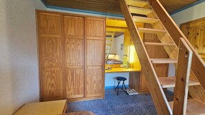 A bedroom with a wooden wardrobe, a desk with a lamp, and a wooden staircase. - Baltic Sea, Schlei and surroundings (Norderbrarup)