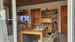 A living room with a wooden table, a television, and a bookshelf filled with books and decorative items. - Baltic Sea, Schlei and surroundings (Norderbrarup)