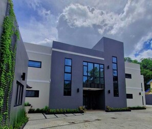 A modern building with a flat roof, large windows, and a paved entrance area. - Modern 3 BR- 3 bath, Cascade, 5 mins from Downtown POS, Pool (Port of Spain)
