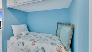Quarto com cama, cortinas brancas e um armário no teto.