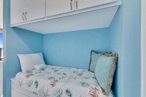 Ein Schlafzimmer mit einem Bett, weißen Vorhängen und einem Schrank an der Decke.