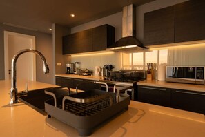 Una cocina moderna con un lavamanos de acero inoxidable, una campana extractora integrada y un microondas.