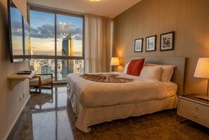 Ein Hotelzimmer mit einem großen Bett, einem Schreibtisch und Blick auf die Stadt.