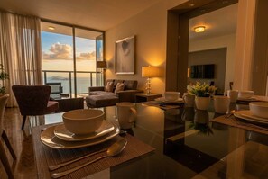 A hotel room with a dining area, a sofa, a TV, and a view of the sea. - Apartamento 50K con vista al mar con 1 dormitorio (Panamá)