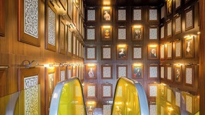 Un interno con una scala centrale, pannelli in legno e opere d'arte incorniciate alle pareti.