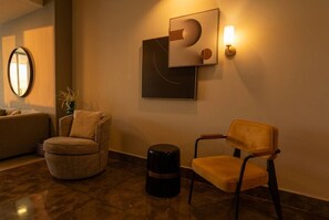 Ein modernes Interieur mit einem runden Sessel, einer Couch und einer Wandleuchte.