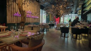 A restaurant interior with tables set for dining, a bartender preparing drinks, and a neon sign on the wall. - 31J Apto en Yoo, Lujoso con Vista al Mar de 2 rec (Panamá)