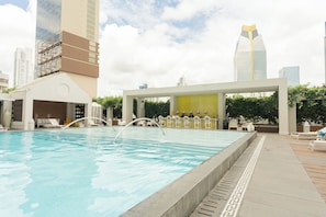 A swimming pool with lounge chairs and a bar area, surrounded by high-rise buildings. - 31J Apto en Yoo, Lujoso con Vista al Mar de 2 rec (Panamá)