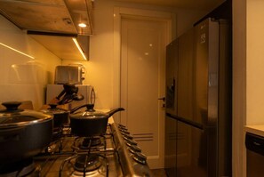 Eine Küche mit Herd, Töpfen, Mikrowelle und Kühlschrank.