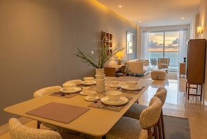 A dining area with a table set for four, a potted plant, and a view of the ocean through large windows. - Apto 48C con vista al mar y con 1 dormitorio (Panamá)