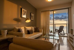 A modern living room with a sofa, a glass coffee table, and a view of the sea through large windows. - 32B Apto en Yoo con Vista al mar en Avenida Balboa (Panamá)