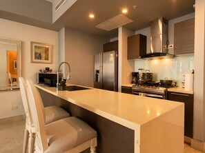 A modern kitchen with a central island, stainless steel appliances, and a built-in oven. - 33D Apto Yoo Panamá, vista al mar de 1 recámara (Panamá)