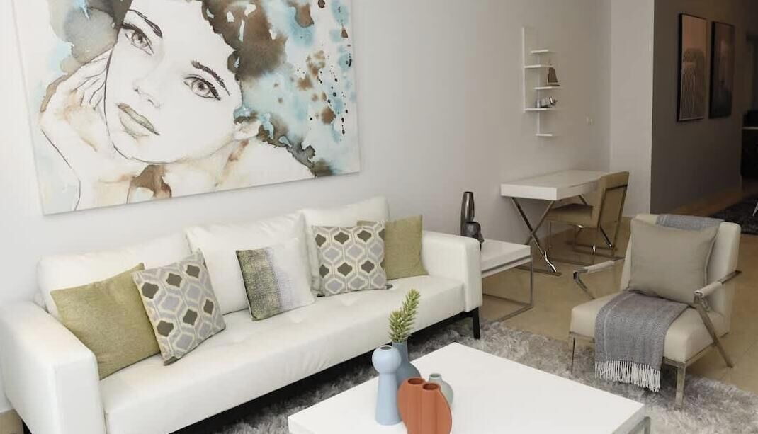 A modern living room with a white sofa, a coffee table, and a dining area with a white table and chairs.