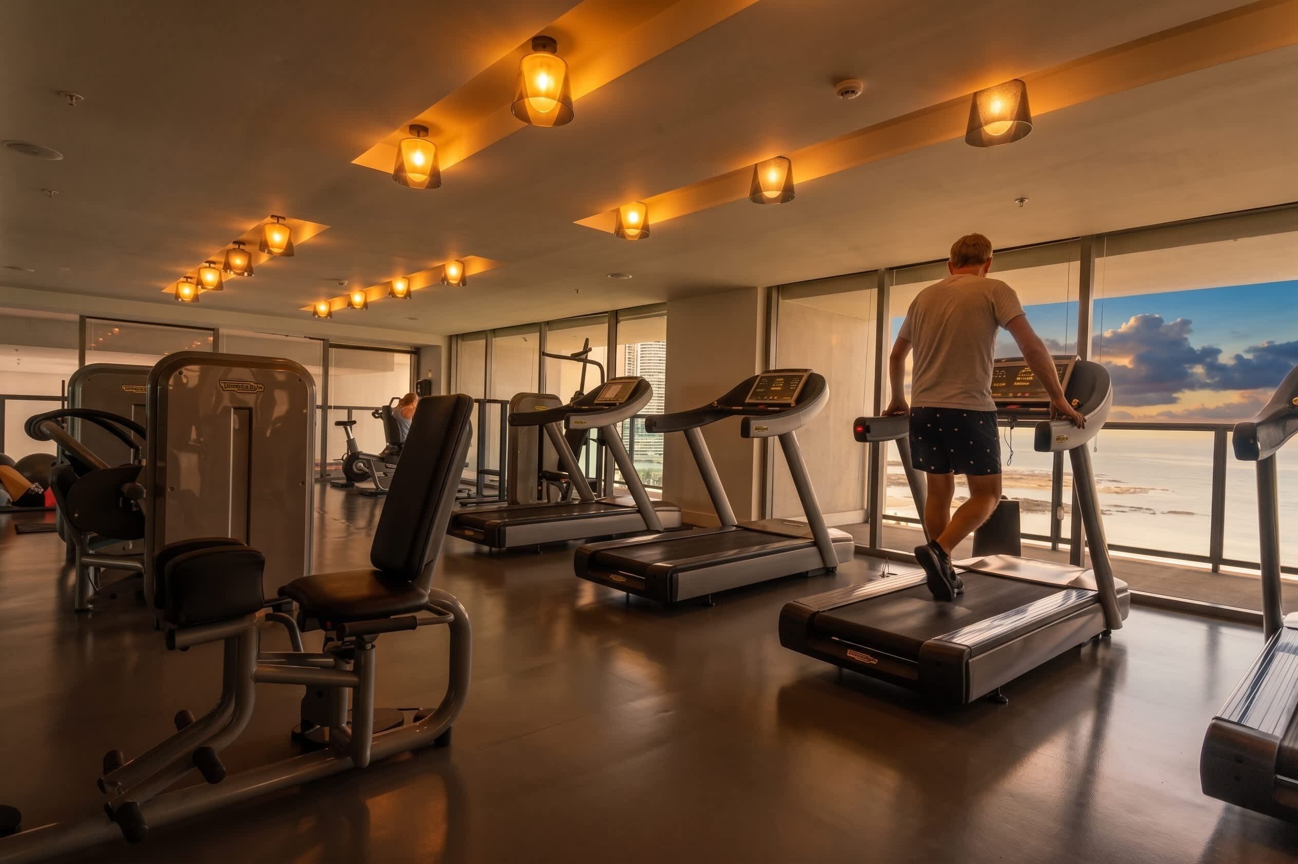 Ein Fitnessstudio mit Laufbändern, Trainingsgeräten und großen Fenstern mit Blick.