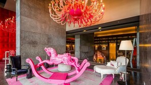 A lobby with a chandelier, a pink horse sculpture, and a white sofa. - Lujoso Apto 34A, vista al mar con dos recamaras (Panamá)