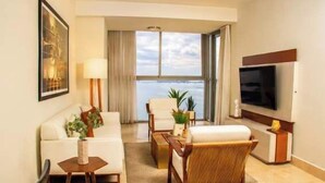 A hotel room with a sofa, armchair, TV, and a view of the sea. - Lujoso Apto 34A, vista al mar con dos recamaras (Panamá)