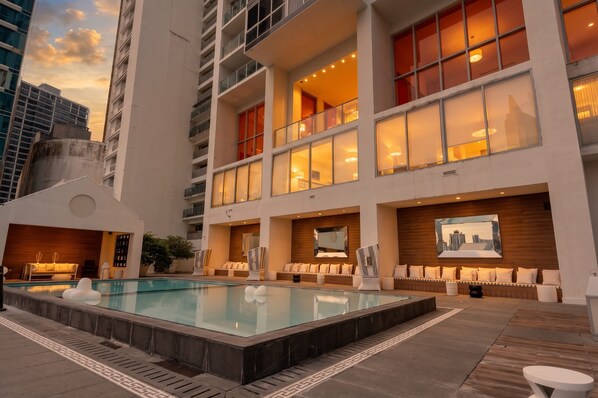 Ein modernes Hotel mit Dachpool, mehreren Balkonen und Blick auf die Skyline der Stadt.