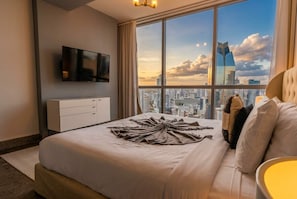 A hotel room with a large bed, a television on the wall, and a city view. - Apto 33H en YOO, vista a la ciudad con 1 recamara (Panamá)
