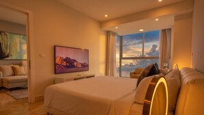 Quarto de hotel moderno com uma cama grande, um sofá, uma TV e uma janela com vista.