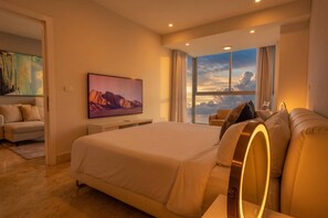 Ein modernes Hotelzimmer mit einem großen Bett, einer Couch, einem Fernseher und einem Fenster mit Blick.