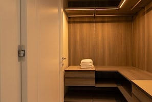 Ein begehbarer Kleiderschrank mit Holzböden und einem gefalteten Handtuch auf der obersten Ablage.