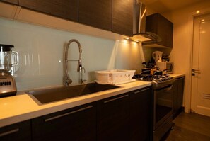 A modern kitchen with a built-in stove, a sink, and a microwave. - 25J Lujoso Apto en YOO, vista al mar con 2 recámaras (Panamá)