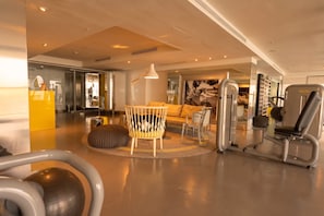 A modern gym with exercise equipment, a yoga mat, and a cozy seating area with a lamp. - 25J Lujoso Apto en YOO, vista al mar con 2 recámaras (Panamá)