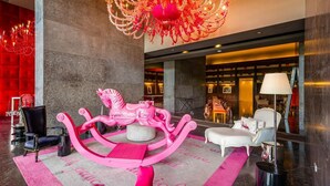 Eine Lobby mit einer rosa Karussell, einer Chandelieber und einer roten Wand.