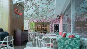 An indoor dining area with tables, chairs, and a sofa. There is a neon sign on the wall and a decorative archway with flowers. - 23 A Espacioso Apto en Yoo con Vista Mar 2 Rec (Panamá)