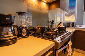 Eine Küche mit einem Herd, Töpfen, einem Mixer und einer Kaffeemaschine.